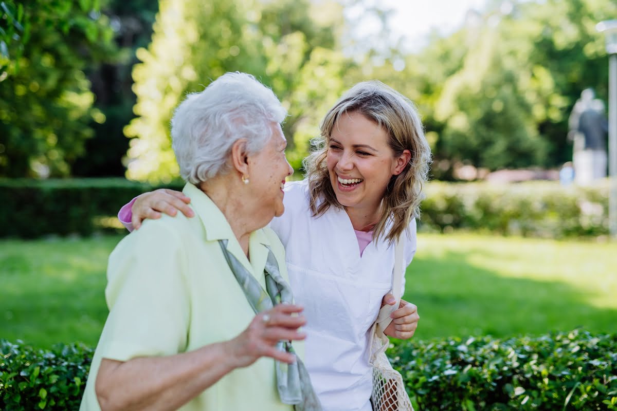 Myths About Assisted Living: Separating Fact from Fiction Smiling Senior Woman and Caregiver Walking Outside_Sunscape™ Boca Raton
