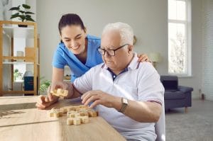 Why Early Dementia Detections Matter Caregiver helping an older adult with a puzzle in a memory care community