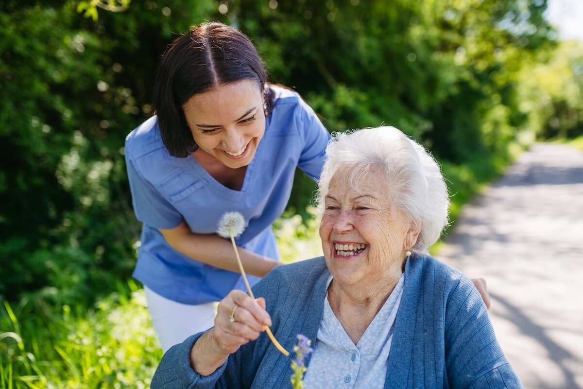 7 Vital Signs It’s Time for Assisted Living Caregiver with an older woman holding a flower