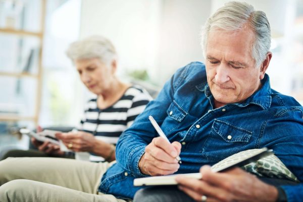 two older adults writing in notebook two older adults writing in notebook