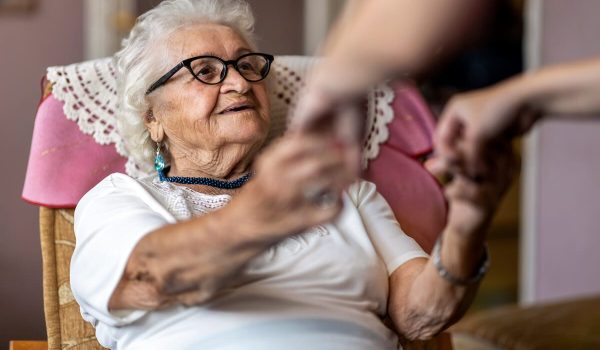 Older woman with dementia holding hands with a relative