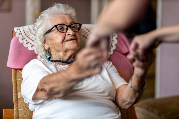 Older woman with dementia holding hands with a relative Older woman with dementia holding hands with a relative